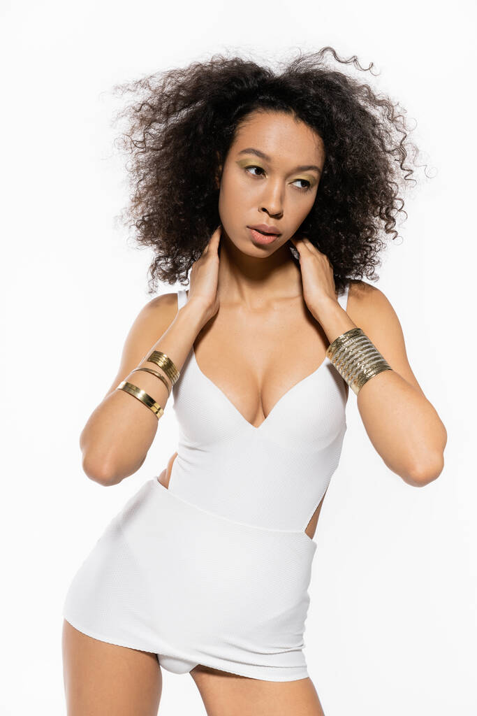 joven modelo afroamericano con pulseras doradas en las manos posando en traje de baño aislado en blanco  - Foto, Imagen