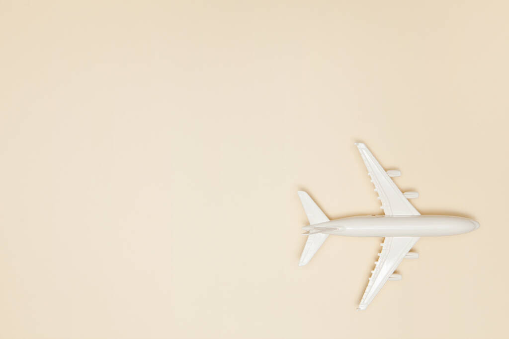 Μοντέλο αεροπλάνου. Λευκό αεροπλάνο σε ανοιχτό καφέ φόντο. Ταξιδιωτικές διακοπές. Θερινό φόντο. Επίπεδο lay, πάνω όψη, αντιγραφή χώρου. - Φωτογραφία, εικόνα