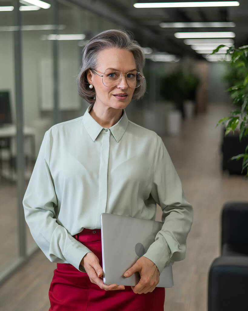 Kypsä valkoihoinen nainen seisoo kannettava tietokone toimistossa - Valokuva, kuva