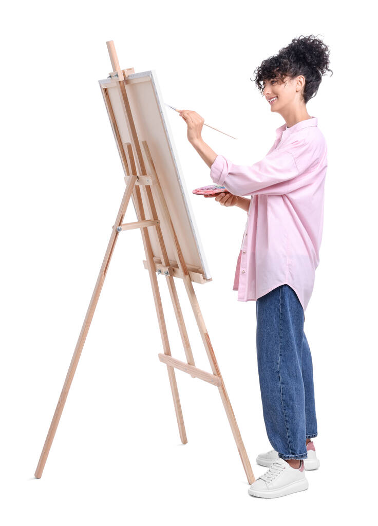 Νεαρή γυναίκα ζωγραφική στο καβαλέτο με καμβά σε λευκό φόντο - Φωτογραφία, εικόνα
