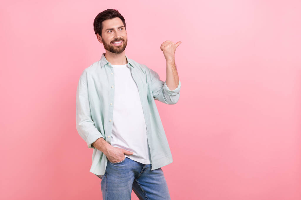 Foto portret van mooie jonge man look point lege ruimte winkelen promo gekleed stijlvolle blauwe kledingstuk geïsoleerd op roze kleur achtergrond. - Foto, afbeelding