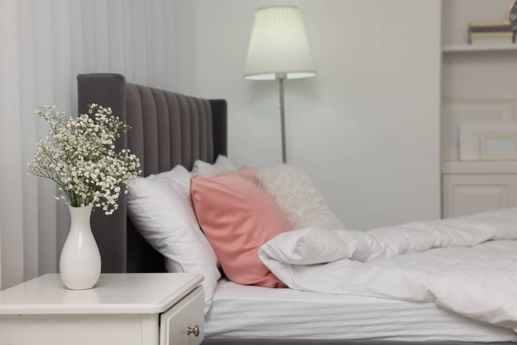 Стильний інтер'єр спальні зі зручним ліжком, тумбою і лампою
 - Фото, зображення