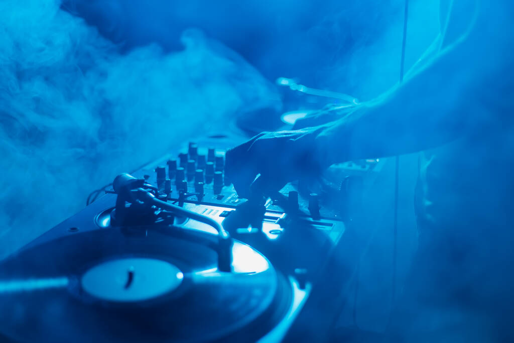 Σιλουέτα ενός κλαμπ DJ που αναμιγνύει μουσική σε καπνό στη σκηνή. Επαγγελματικός δίσκος jokey παίζει που σε techno κόμμα  - Φωτογραφία, εικόνα