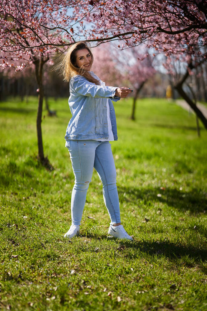 Mujer joven de Asia oriental disfrutando de la primavera en un parque con árboles florecientes - Foto, imagen