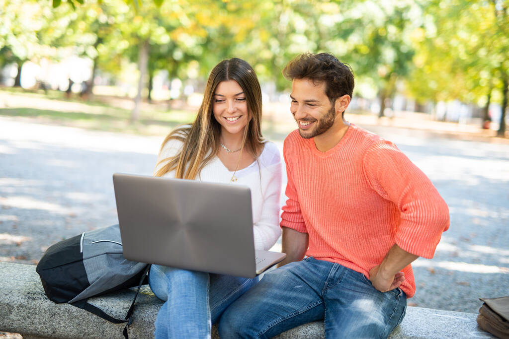 College students using a laptop computer in a park, young people and technology concept - Photo, Image