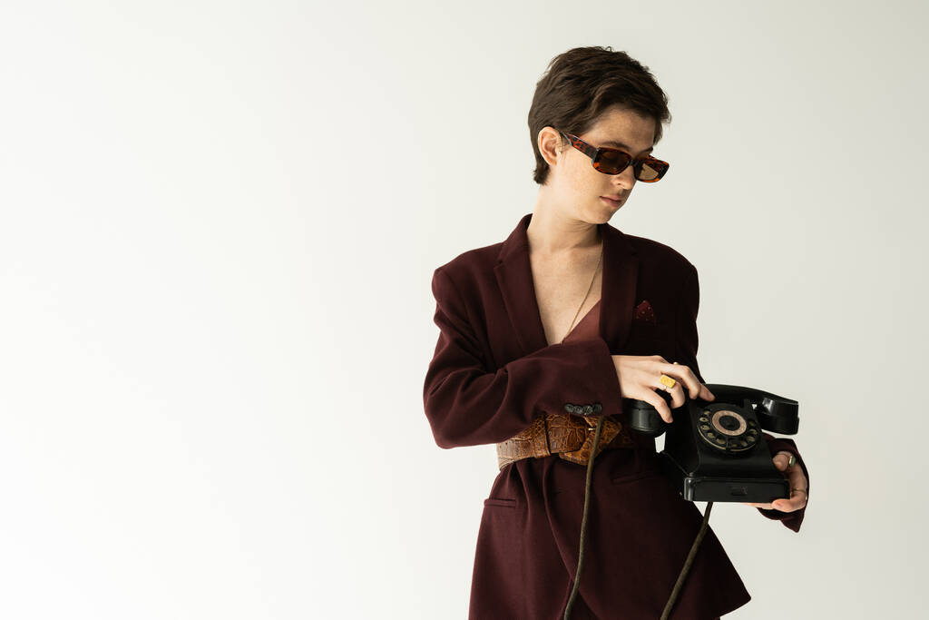 barna nő divatos kabát bőr öv áll vintage telefon szürke háttér - Fotó, kép