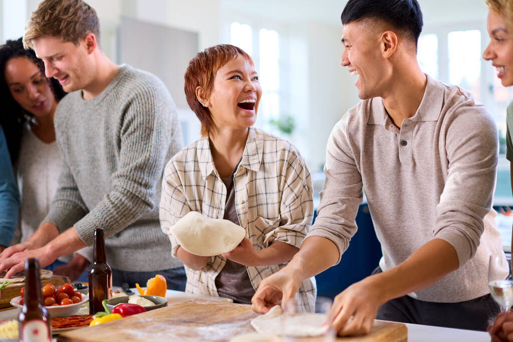 Gruppo di amici a casa in cucina con fare pizze per la festa insieme - Foto, immagini