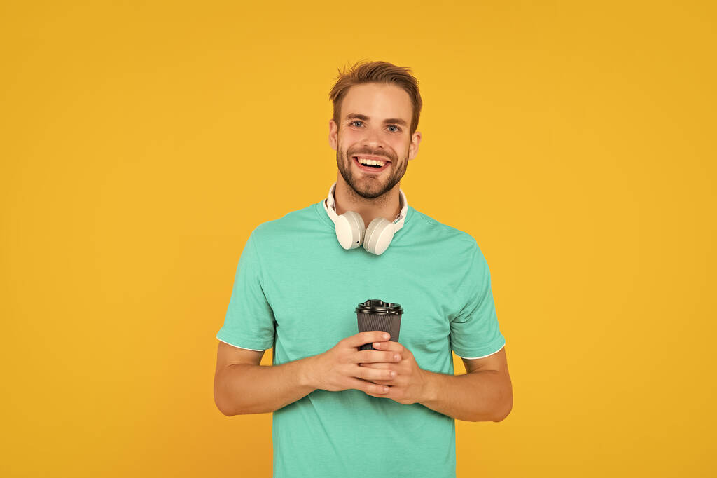 happy man in modern earphones with coffee cup. online education. back to school. young guy in headphones. music lover. listen to music. wireless device accessory. new technology. - Zdjęcie, obraz
