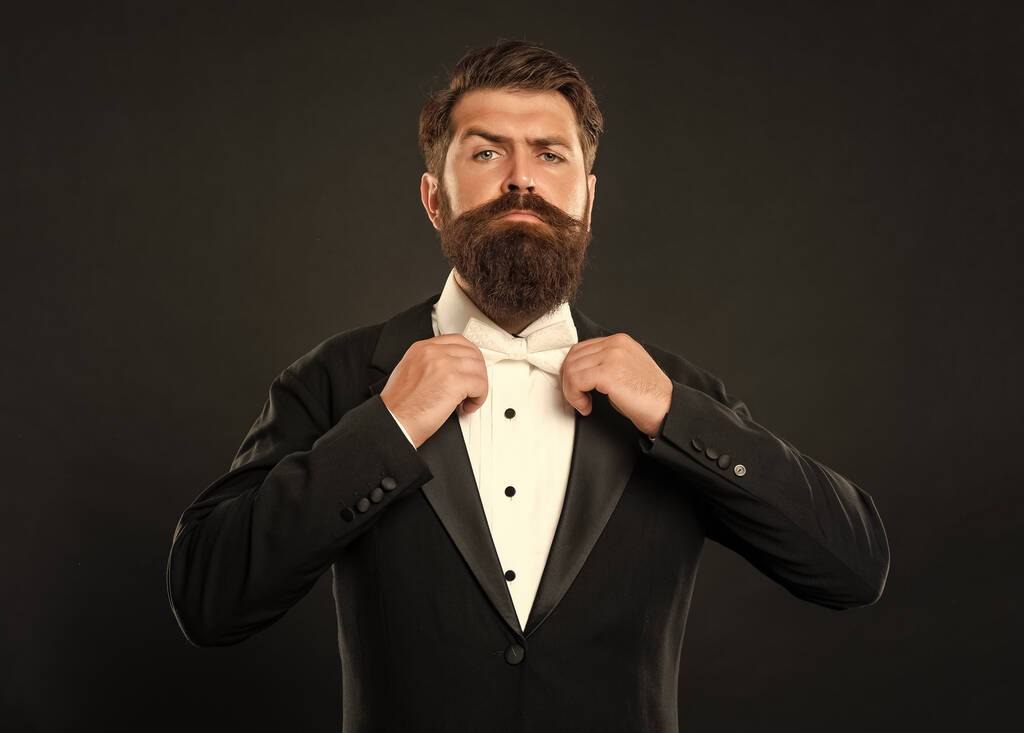 bearded groom in tuxedo on black background, bow tie. - Photo, Image