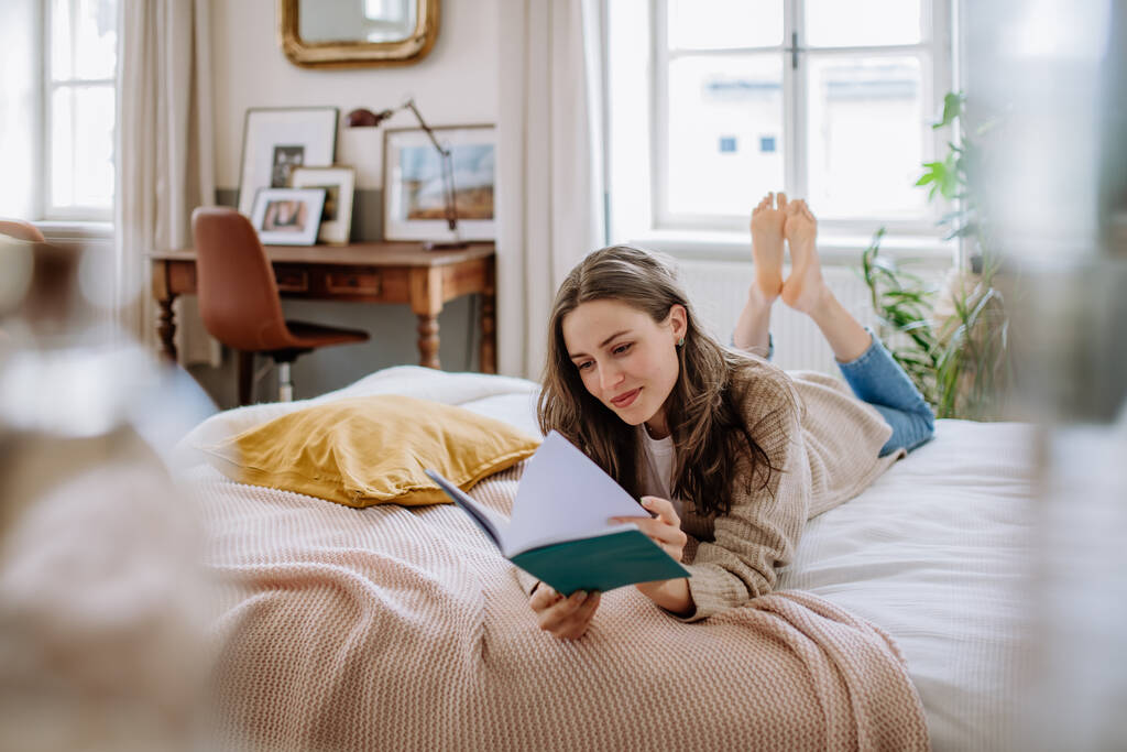 Mujer joven disfrutando del tiempo libre en su apartamento, leyendo un libro. - Foto, imagen