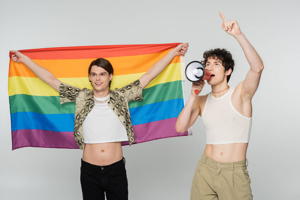 nuori ei-binary henkilö huutaa megafoni lähellä positiivinen kumppani lgbt lippu eristetty harmaa - Valokuva, kuva