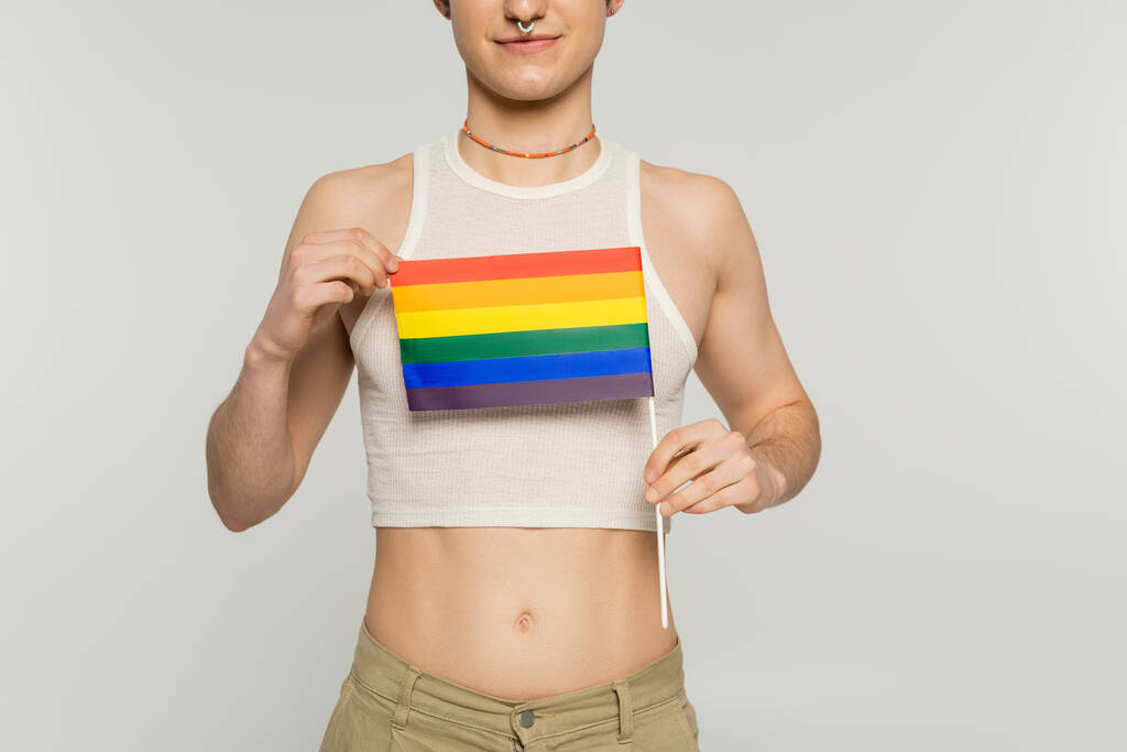 Gri üzerine izole edilmiş küçük lgbt bayrağı taşıyan genç panseksüel modelin kısmi görünümü - Fotoğraf, Görsel