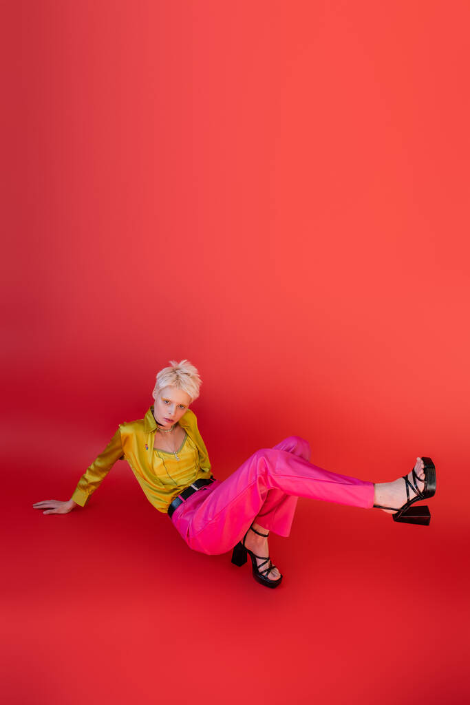 in voller Länge Albino-Frau in Sandalen und trendigem Outfit posiert auf karminrosa  - Foto, Bild