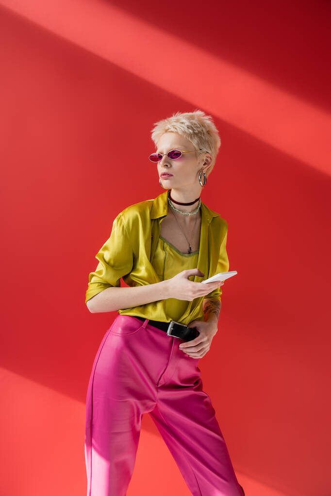 tetovált albínó nő divatos napszemüveg okostelefon carmine rózsaszín  - Fotó, kép
