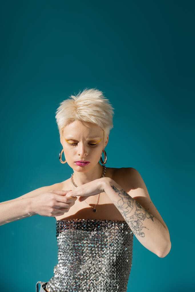 tetovált albínó modell divatos ruhát pózol a kék háttér  - Fotó, kép
