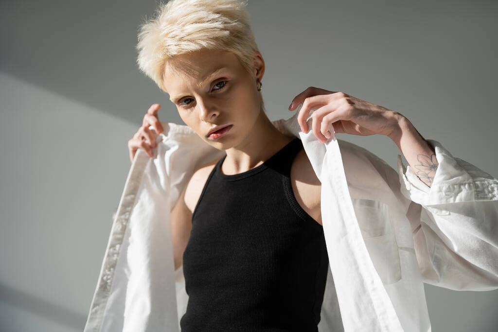 albiino nainen musta toppi yllään valkoinen paita harmaa tausta - Valokuva, kuva