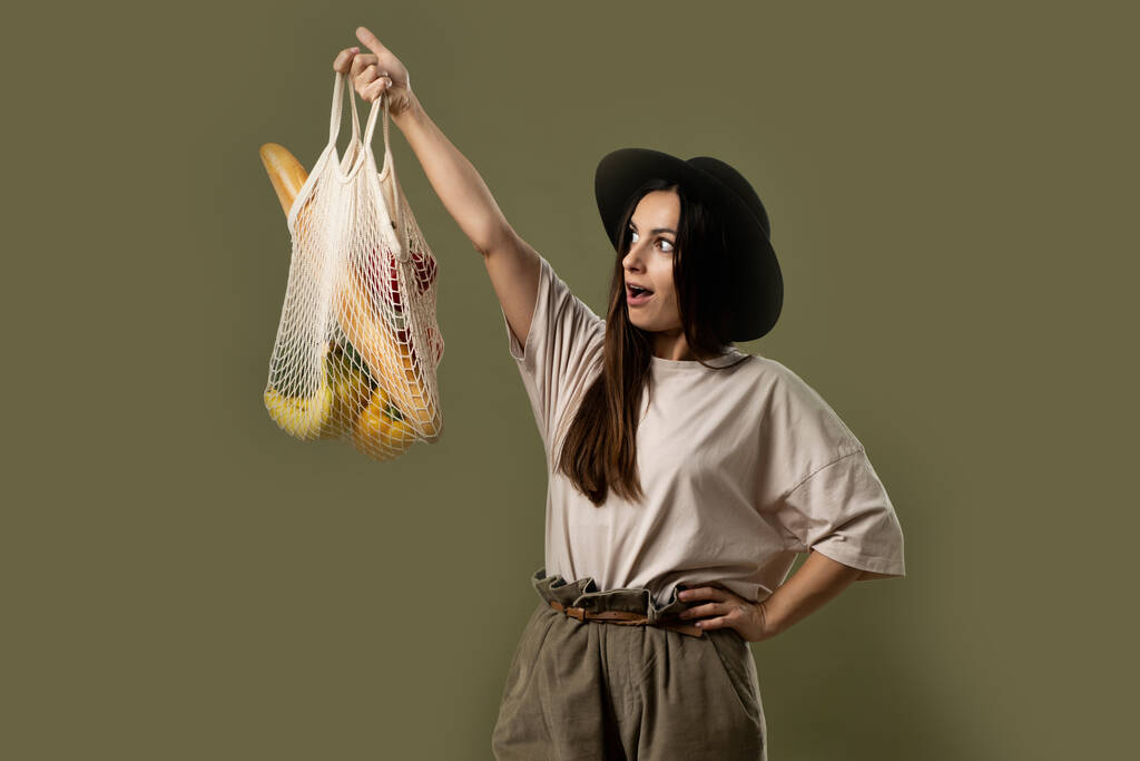 Concepto de Ecología. Mujer sosteniendo bolsa de algodón con verduras. Bolsa ecológica reutilizable para ir de compras. Concepto de cero residuos. Estilo de vida ecológico. Fondo blanco aislado - Foto, imagen