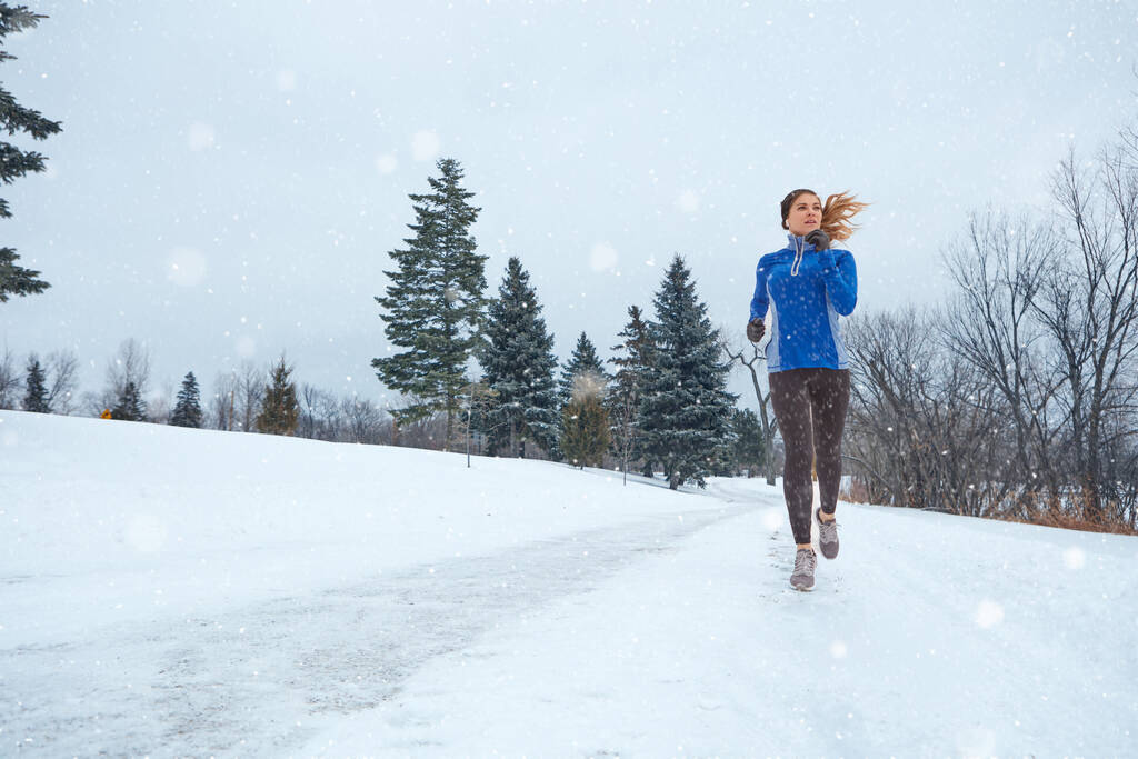 Une course est exactement ce dont vous avez besoin pour réchauffer votre corps. une femme portant des vêtements chauds lors d'une course à travers la neige - Photo, image