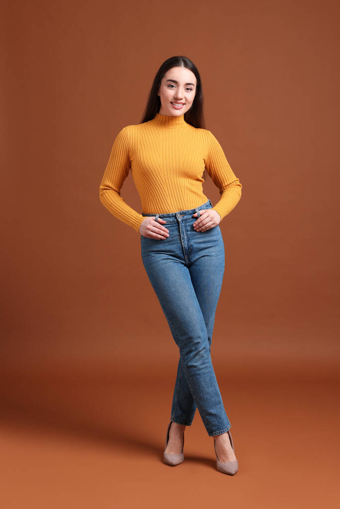 Молода жінка в стильних джинсах на коричневому фоні
 - Фото, зображення