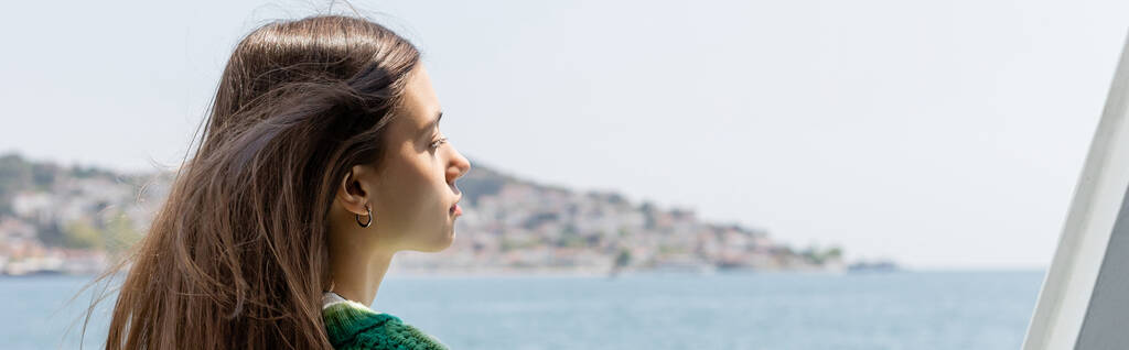 Side view of young brunette woman looking at blurred sea and Princess islands in Turkey, banner  - Photo, Image