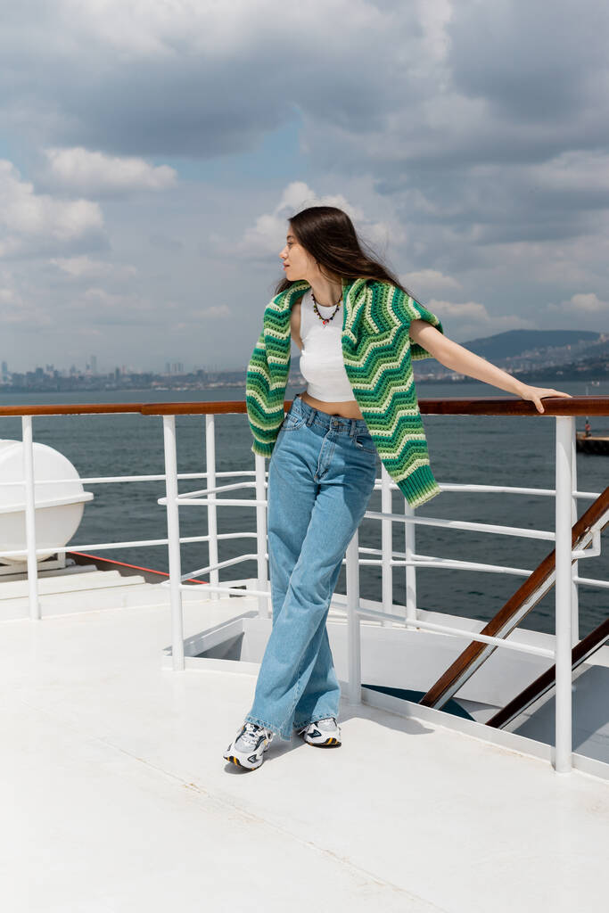 Vista laterale della donna bruna che distoglie lo sguardo mentre è in piedi sul traghetto in Turchia  - Foto, immagini