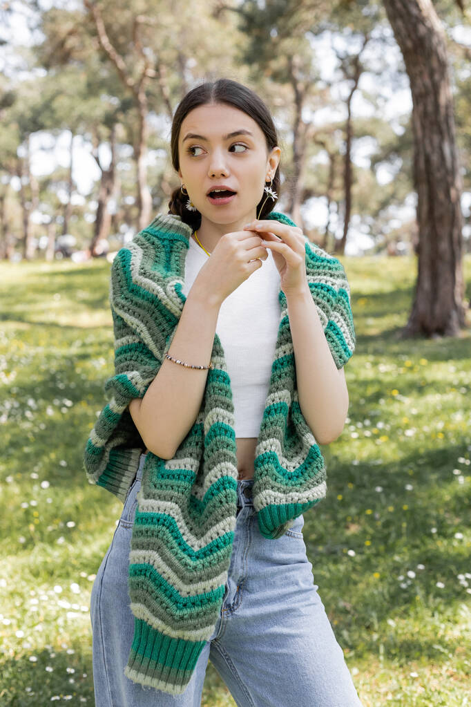 夏の公園でデイジーの肩にニットセーターを着た驚きの女性  - 写真・画像