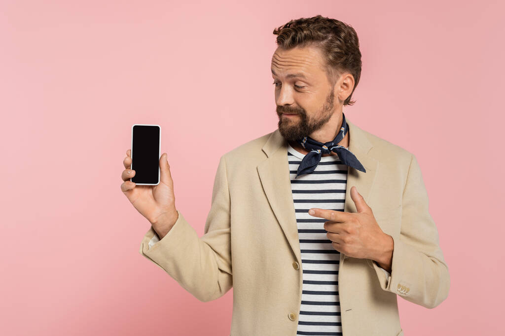 homem francês barbudo em blazer e cachecol pescoço apontando para smartphone com tela em branco isolado em rosa  - Foto, Imagem