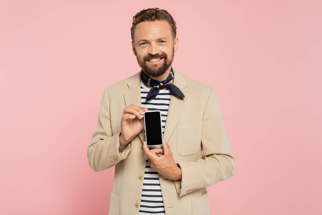 šťastný francouzský muž v blejzru a krku šála držení smartphone s prázdnou obrazovkou izolované na růžové  - Fotografie, Obrázek