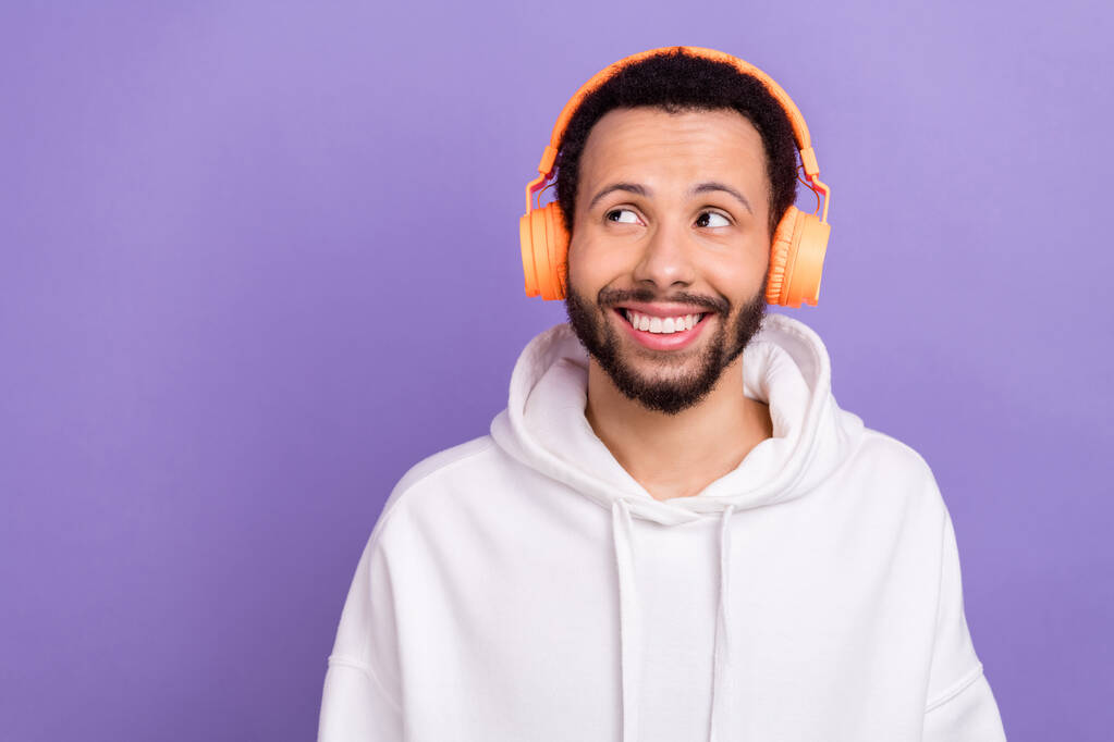 Portret myślącej wesołej osoby zębaty uśmiech wygląd pusty przestrzeń słuchać muzyki słuchawki izolowane na fioletowym tle koloru. - Zdjęcie, obraz