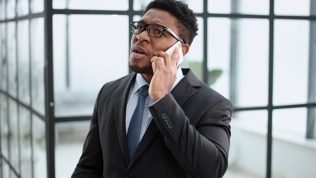 Porträt eines afroamerikanischen Geschäftsmannes, der vor dem Büro steht und telefoniert - Foto, Bild