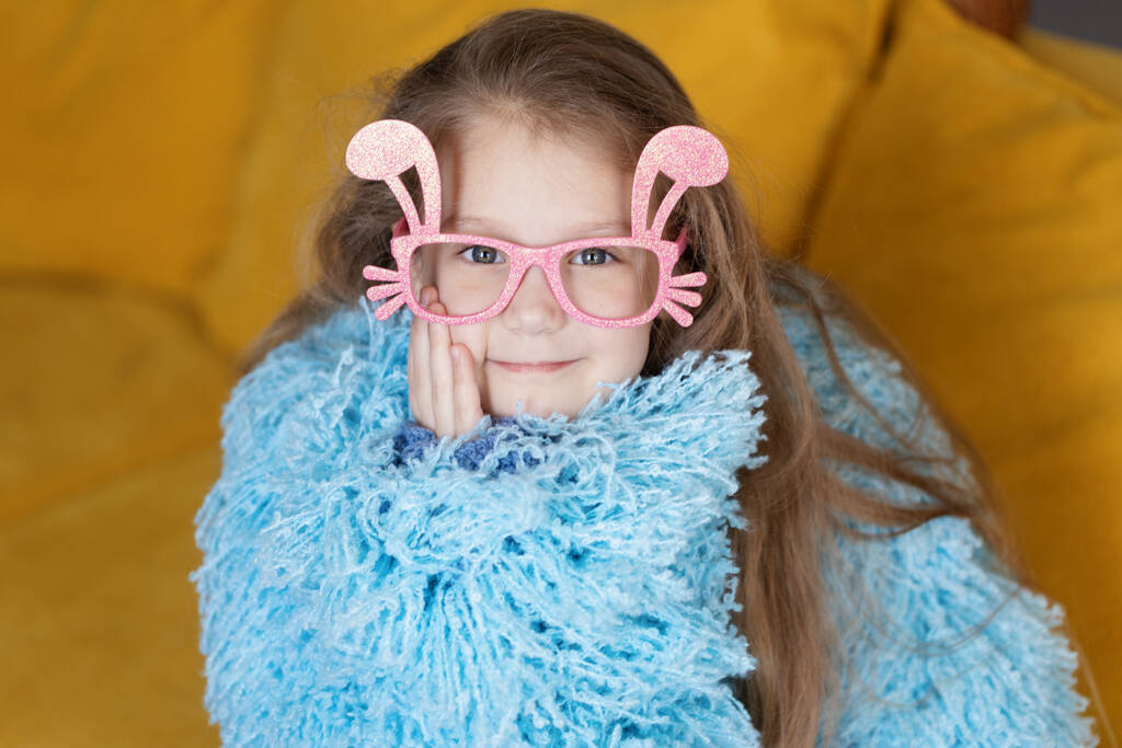 Cute little child girl  in blue fluffy coat wearing bunny ears glasses a on Easter day. Easter girl portrait, funny emotions, surprise.	 - Fotografie, Obrázek