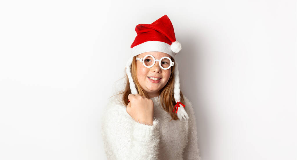 Redhead girl with freckles shows yes, behaved well and receives a gift from Santa Claus, isolated on a white background. - Photo, Image