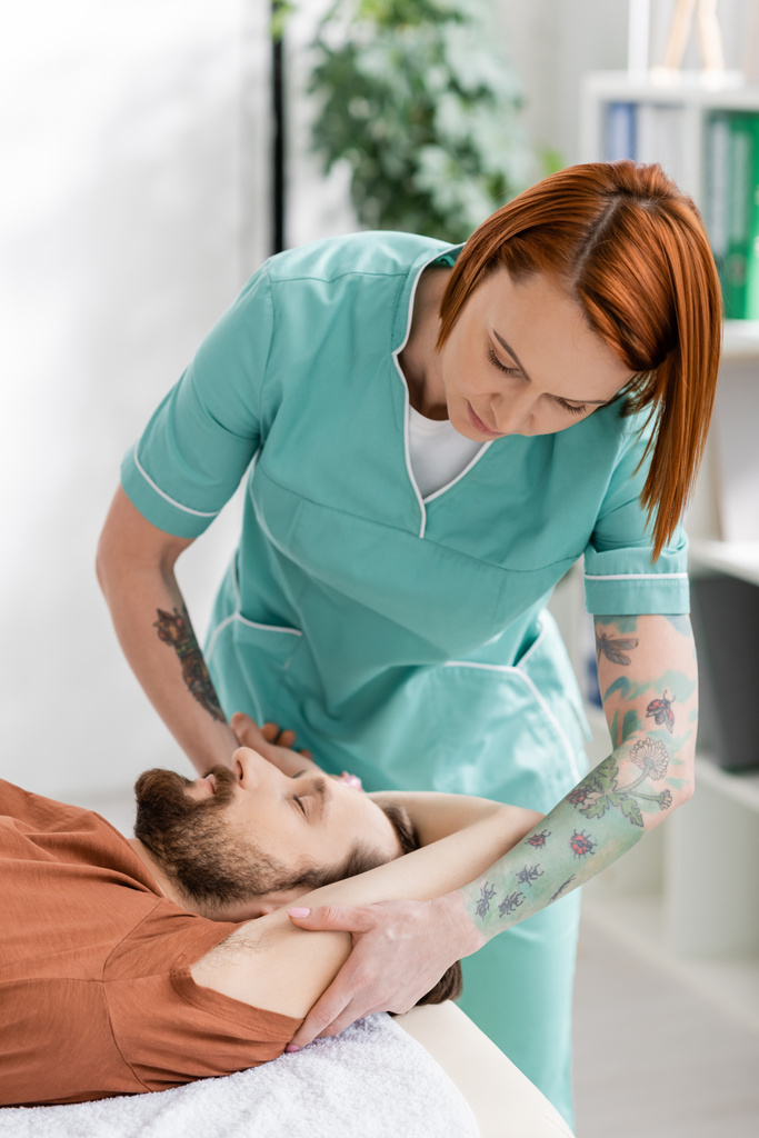 рудий хіропрактик масажна рука бородатого чоловіка під час відновлювальної терапії в консалтинговій кімнаті
  - Фото, зображення