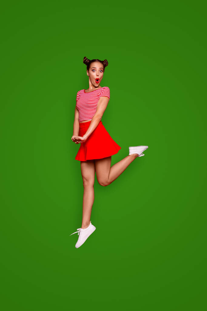 Full-length full-size verticaal weergeven van springen en vroeg zich af brunette vrouw gekleed in kleurrijke lichte kleren geïsoleerd op rode achtergrond. - Foto, afbeelding