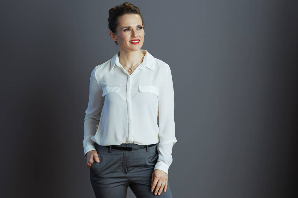 mietteliäs tyylikäs 40-vuotias nainen työntekijä valkoisessa puserossa katselemassa kopiotilaa eristettynä harmaalla taustalla. - Valokuva, kuva