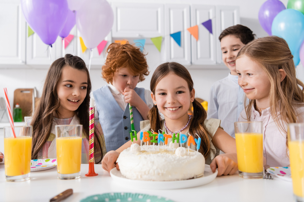 group of happy preteen kids celebrating birthday next to tasty cake during party at home - Photo, Image