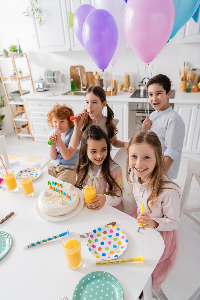 grupo de niños felices soplando cuernos de fiesta durante la celebración del cumpleaños  - Foto, Imagen
