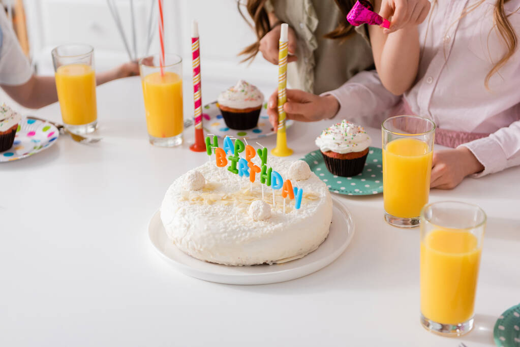 домашний праздничный торт со свечами рядом с кексами и стаканами апельсинового сока  - Фото, изображение