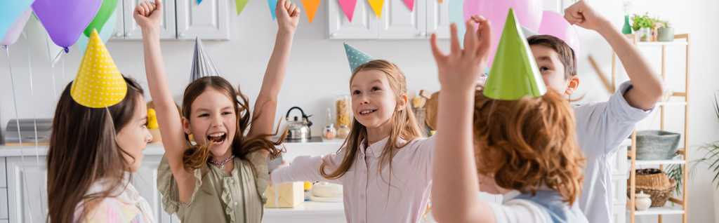 vzrušené děti ve slavnostních čepicích baví při narozeninové oslavě doma, banner  - Fotografie, Obrázek