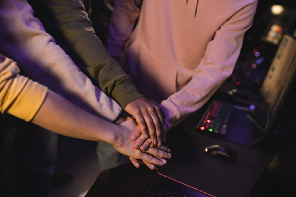 Ausgeschnittene Ansicht von interrassischen Freunden, die Händchen halten in einem Spielklub  - Foto, Bild