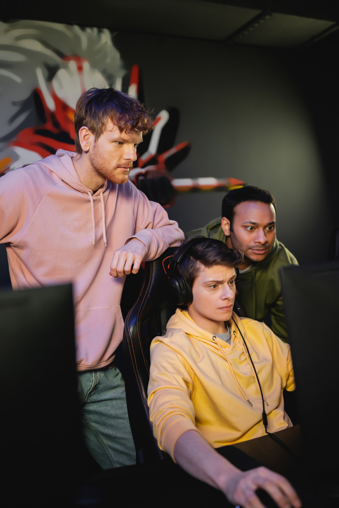 Équipe multiethnique ciblée jouant au jeu vidéo sur ordinateur dans un club de jeu  - Photo, image