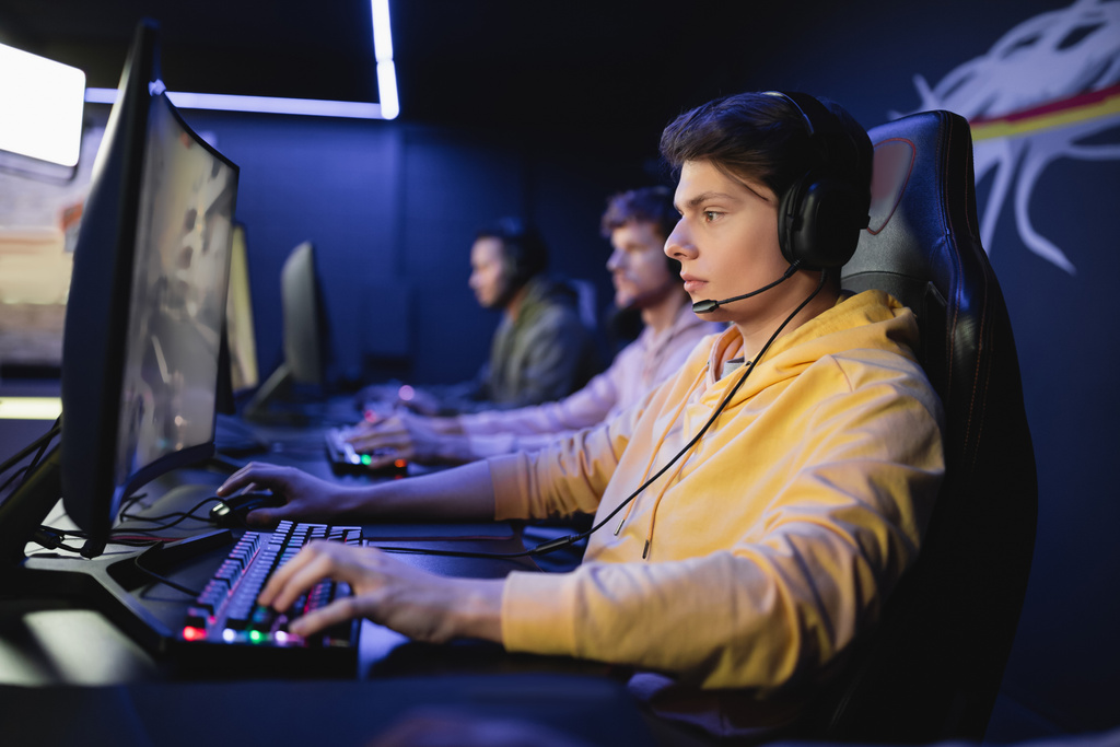 Bilgisayar başında bilgisayar oyunu oynayan kulaklıklı oyuncunun, siber klüpteki takımının yan görüntüsü  - Fotoğraf, Görsel