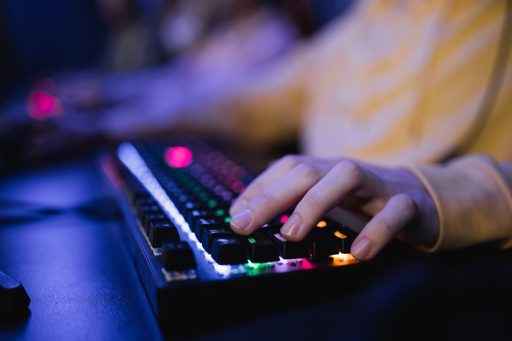 Ausgeschnittene Ansicht des Spielers mittels Tastatur mit Beleuchtung im Cyber-Club  - Foto, Bild