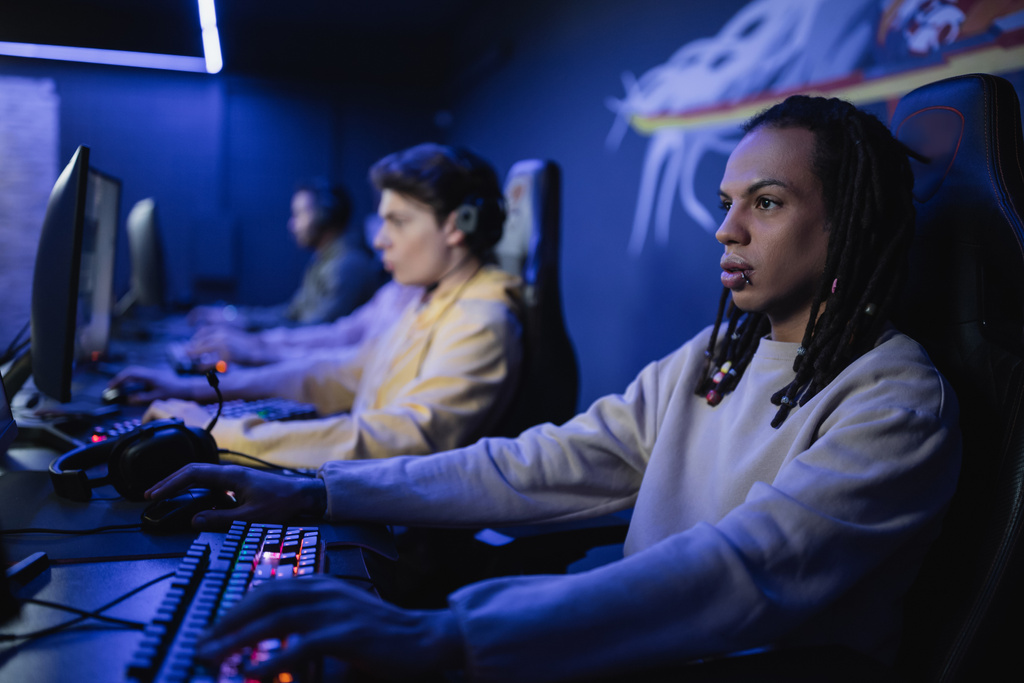 Multiracial hráč hraje videohry s rozmazanými přáteli v kybernetickém klubu  - Fotografie, Obrázek