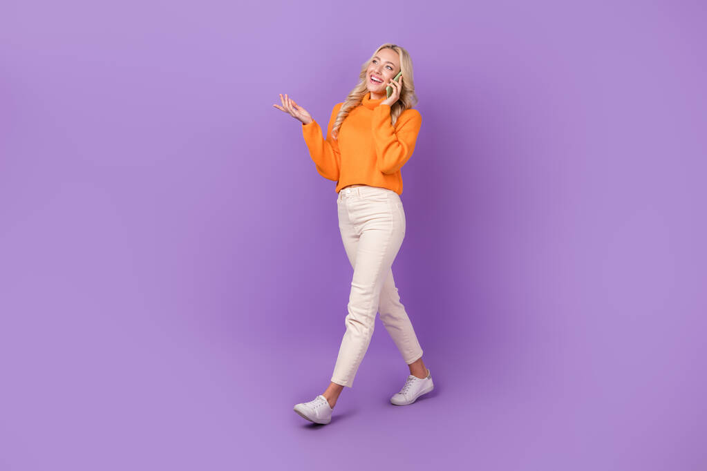 Full size profile portrait of nice cheerful girl walking communicate telephone isolated on purple color background. - Photo, Image