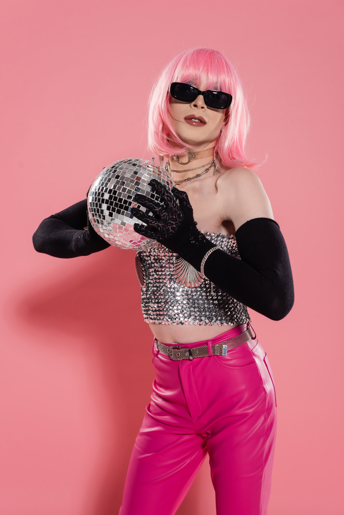 Divatos drag queen napszemüvegben és kesztyű tartja disco labda rózsaszín háttér  - Fotó, kép