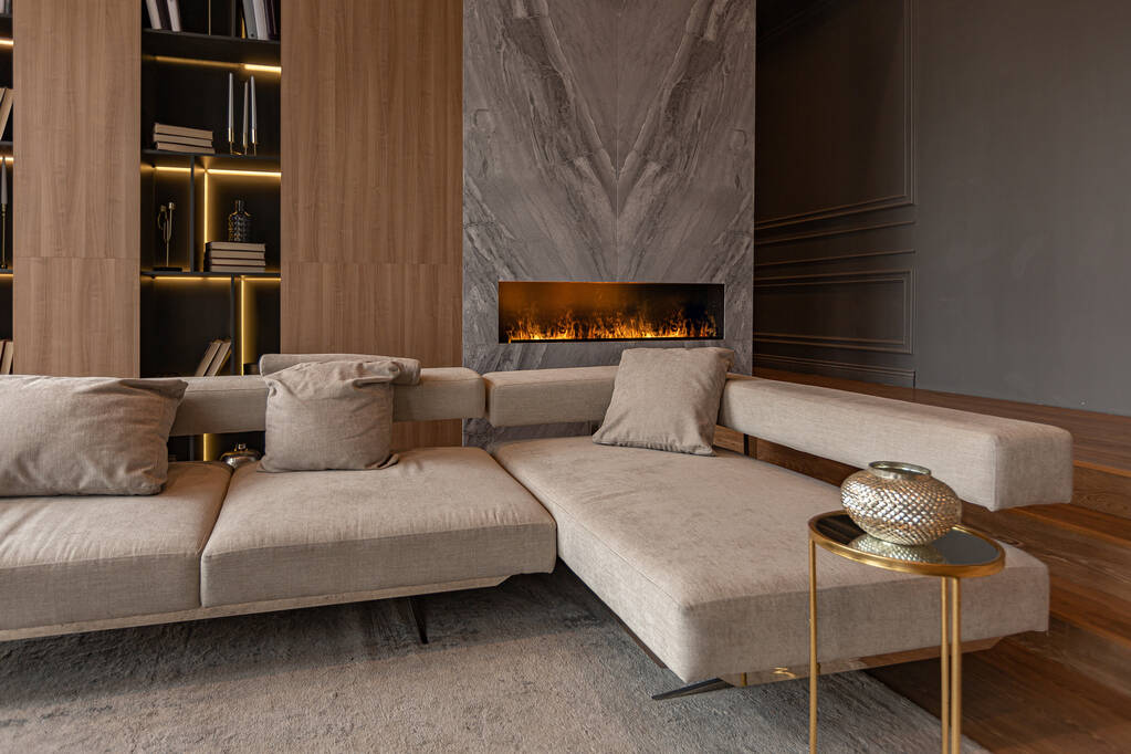 living room, marble wall fireplace and stylish bookcase in chic expensive interior of luxury country house with a modern design with wood and led light, gray furniture with gold elements - Photo, Image