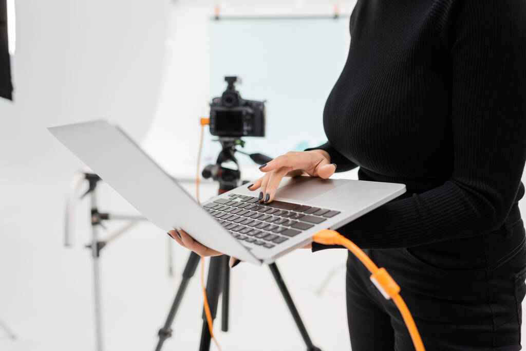 обрізаний вид афроамериканського менеджера контенту з використанням ноутбука біля розмитої цифрової камери на тринозі в фотостудії
 - Фото, зображення