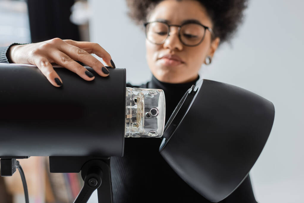 elmosódott afro-amerikai tartalom termelő szemüveg összeszerelése stroboszkóp lámpa fotó stúdió - Fotó, kép