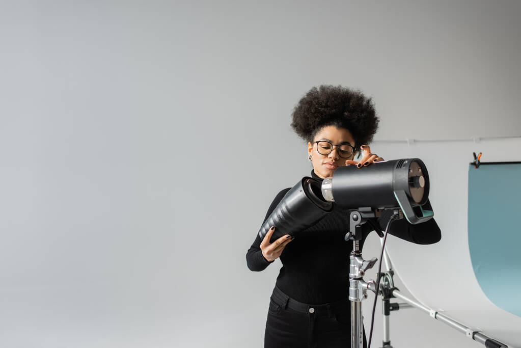 African American content manager assemblaggio torcia stroboscopica mentre si lavora in studio fotografico - Foto, immagini
